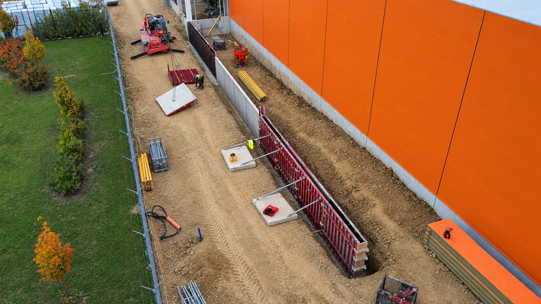 Debnenie steny popri oranžovej fasáde haly Hornbach